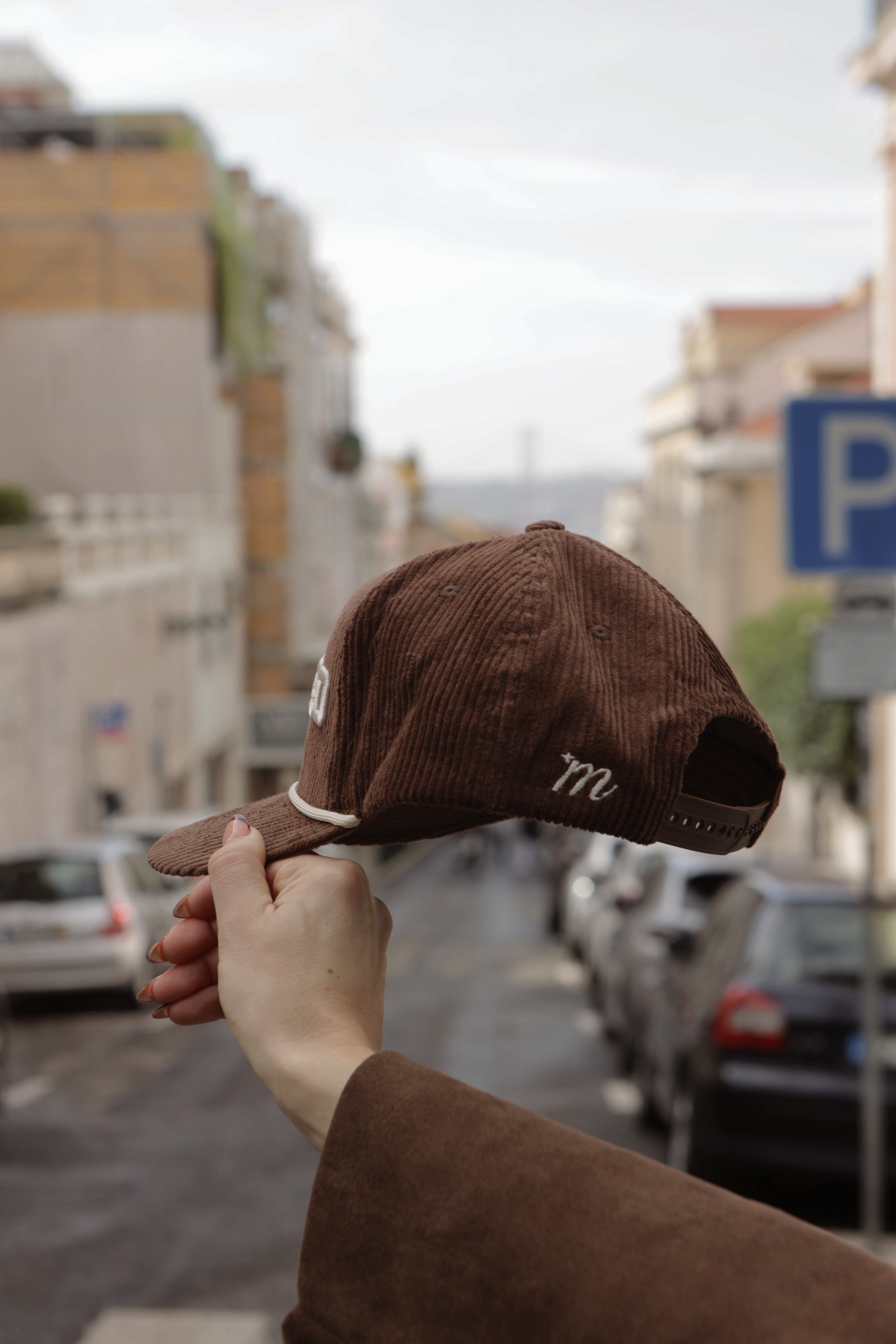Brown cap held by a hand with a blurred indoor background